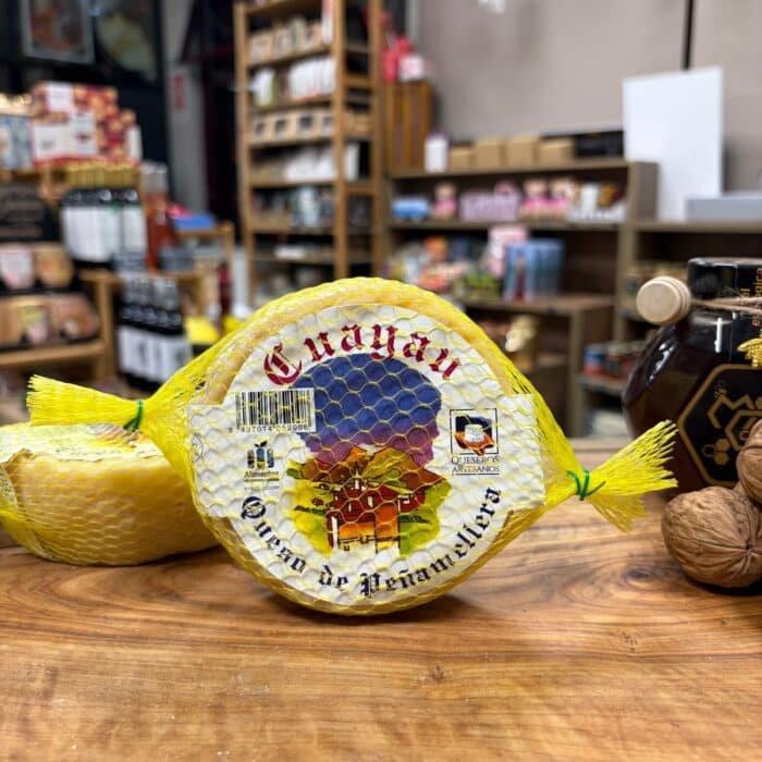 Queso Cuayau de vaca de Peñamellera con su malla amarilla sobre tabla de madera